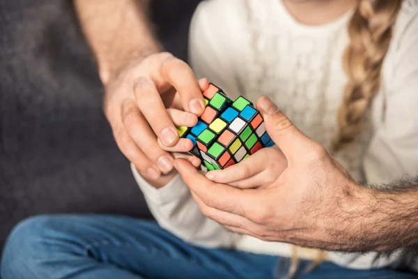 Padre e hija jugando con el cubo de Rubik - foto de stock