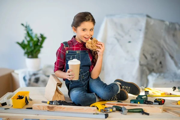 Kleines Mädchen isst in Werkstatt — Stockfoto