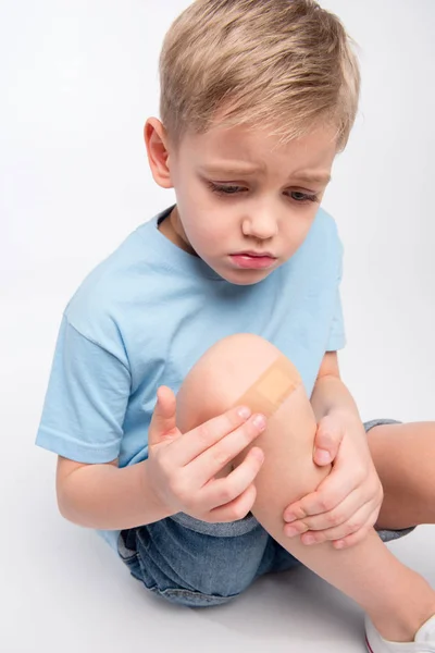 Niño pequeño con parche en la rodilla - foto de stock