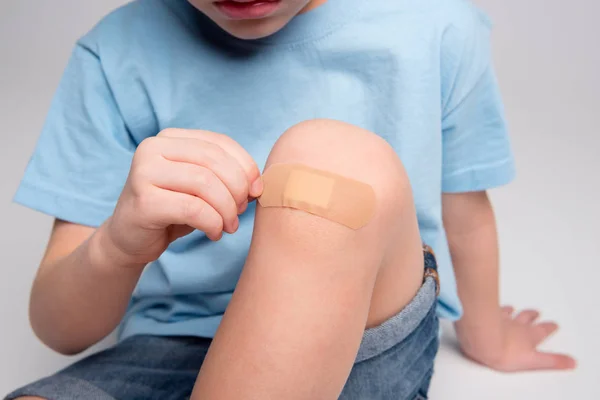 Niño pequeño con parche en la rodilla - foto de stock