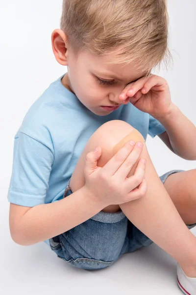 Niño pequeño con parche en la rodilla - foto de stock