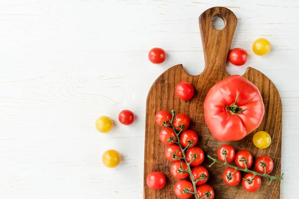 Tomatoes and cutting board — Stock Photo