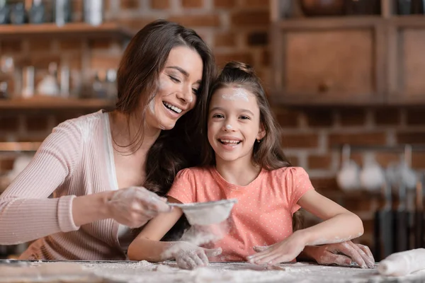 Mother and daughter sifting flour — Stock Photo
