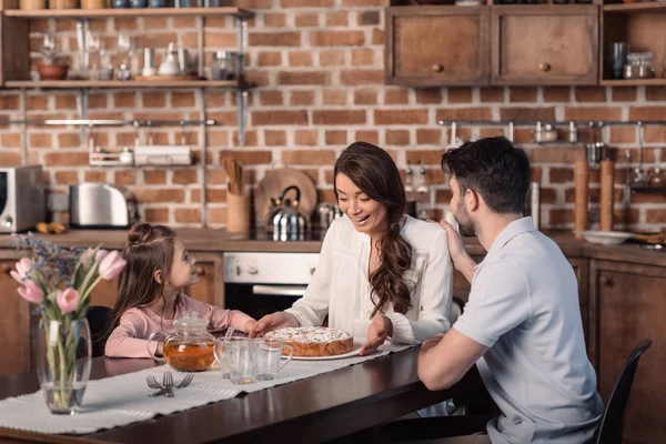 Familia con pastel en la cocina - foto de stock