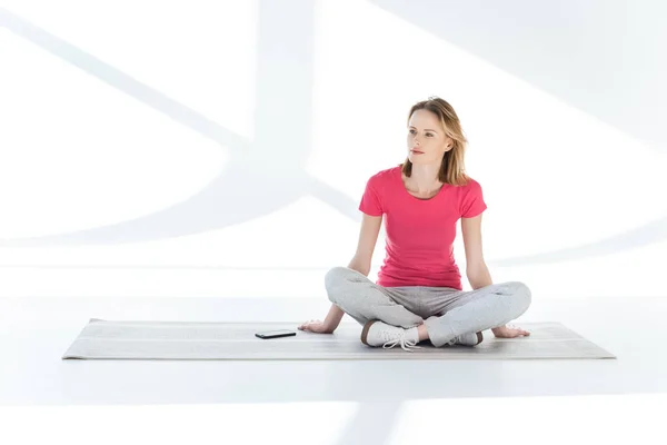 Femme assise sur tapis de yoga — Photo de stock