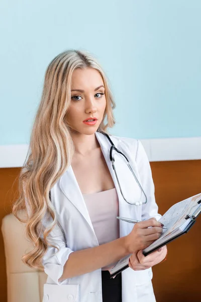 Beautiful doctor writing in notepad — Stock Photo