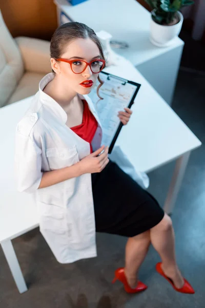 Seductive doctor holding clipboard — Stock Photo