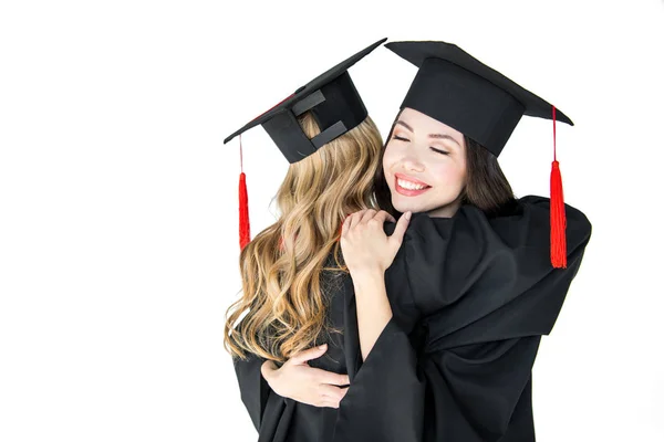 Students in graduation caps hugging — Stock Photo