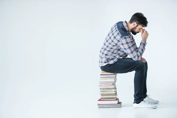 Estudiante sentado en un montón de libros - foto de stock