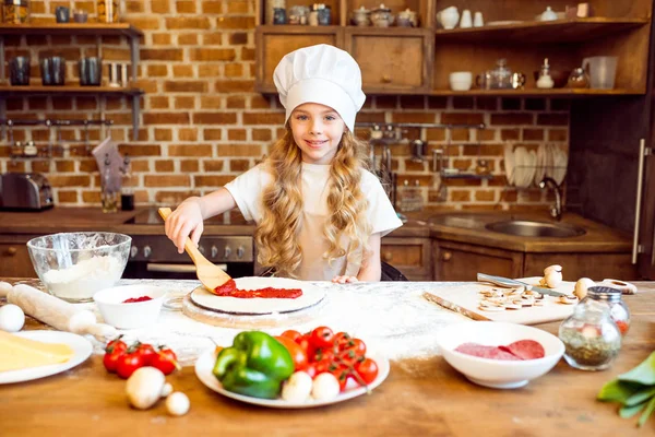 Chica poniendo salsa en la masa - foto de stock