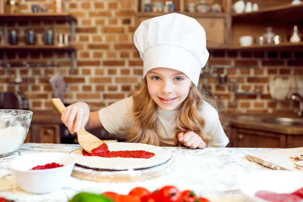 Chica poniendo salsa en la masa - foto de stock