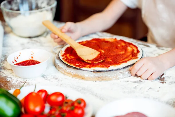 Ragazza mettendo salsa sulla pasta — Foto stock