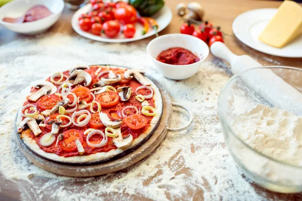 Pizza e ingredientes en la mesa - foto de stock