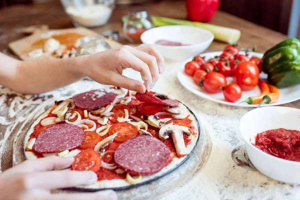 Niño poniendo salchicha en la pizza - foto de stock