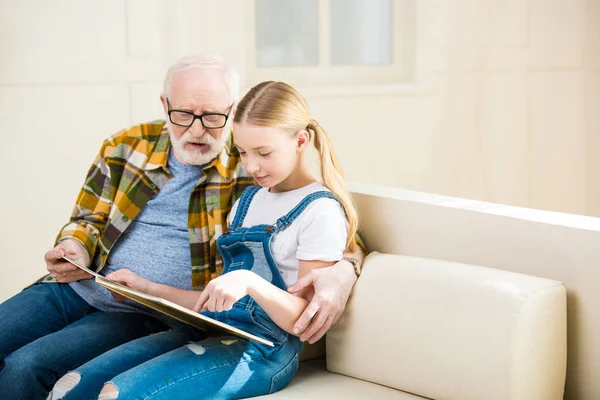 Abuelo con libro de lectura de chica - foto de stock