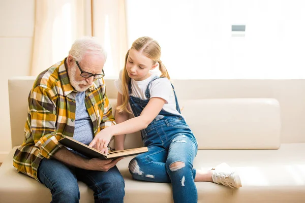 Abuelo con libro de lectura de chica - foto de stock