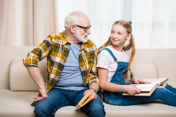 Дедушка с девушкой читает книги — стоковое фото