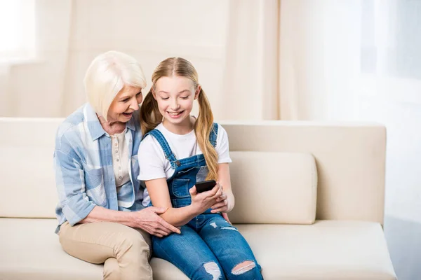 Chica con abuela usando teléfono inteligente - foto de stock