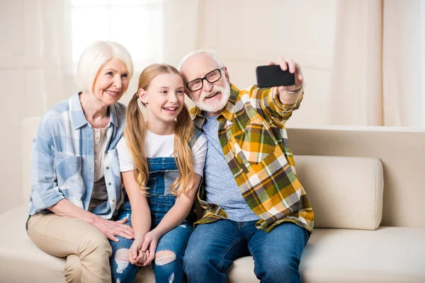 Chica con abuelos tomando selfie - foto de stock