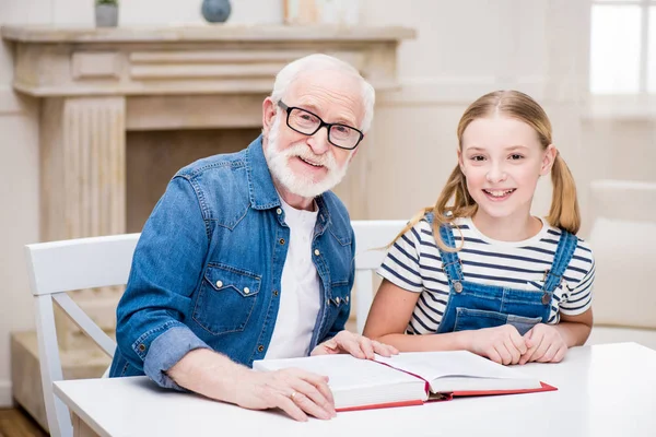Grandfather with girl reading book — Stock Photo