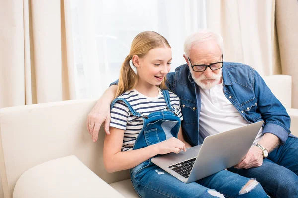 Ragazza con nonno utilizzando il computer portatile — Foto stock