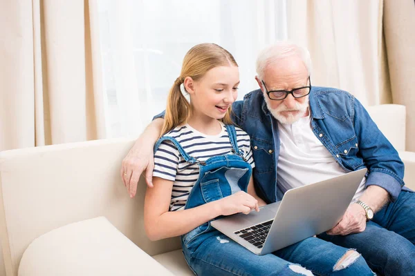 Chica con abuelo usando el ordenador portátil - foto de stock