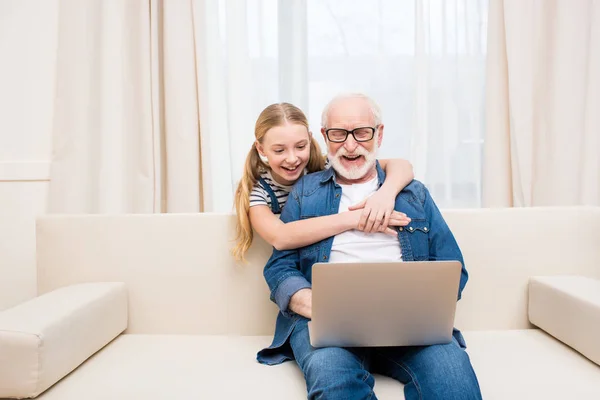 Chica con abuelo usando el ordenador portátil - foto de stock