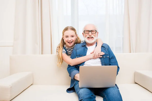 Girl with grandfather using laptop — Stock Photo