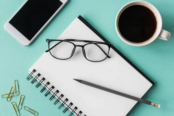 Notebook with cup of coffee and smartphone — Stock Photo