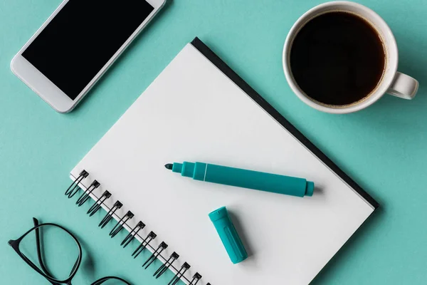 Notebook with cup of coffee and smartphone — Stock Photo