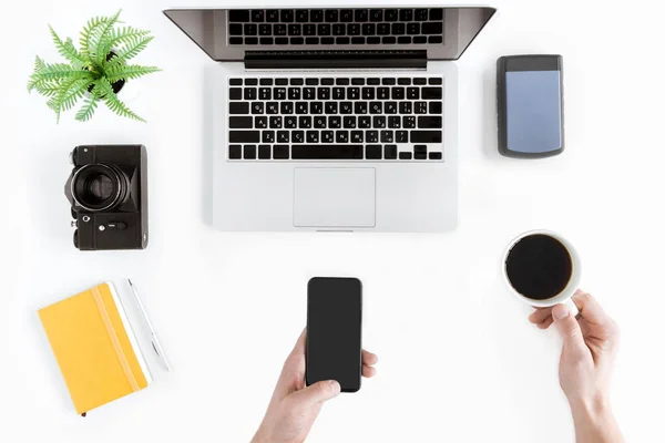 Manos sosteniendo teléfono inteligente y taza de café - foto de stock