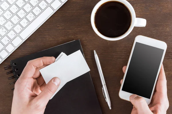 Hands holding smartphone and cards — Stock Photo