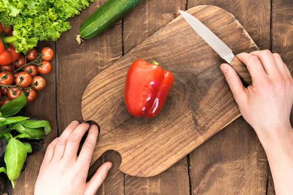 Mãos cortando pimenta na tábua de corte — Fotografia de Stock