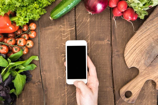 Smartphone sobre mesa con verduras - foto de stock