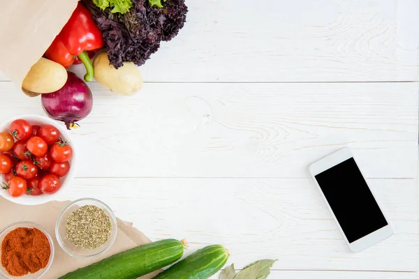 Smartphone y verduras en la mesa - foto de stock