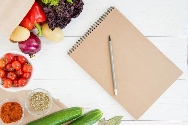 Cuaderno y verduras en la mesa - foto de stock