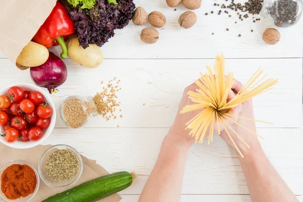 Mani che tengono gli spaghetti crudi — Foto stock