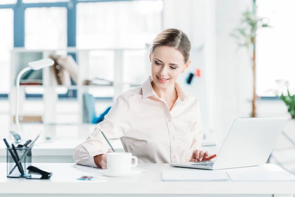 Businesswoman working on laptop at office — Stock Photo