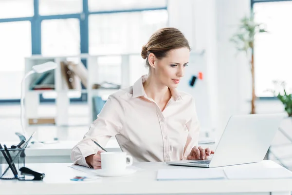 Businesswoman working on laptop at office — Stock Photo