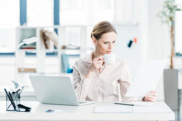 Businesswoman working with documents and drinking coffee — Stock Photo