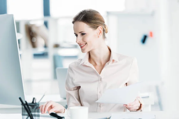 Mujer de negocios que trabaja con documentos y computadoras en la oficina - foto de stock