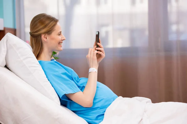 Mujer embarazada con smartphone - foto de stock