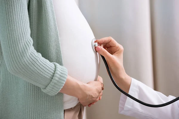 Doctor listening belly of pregnant woman — Stock Photo