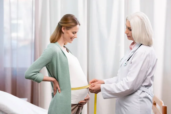 Médico midiendo vientre de mujer embarazada - foto de stock