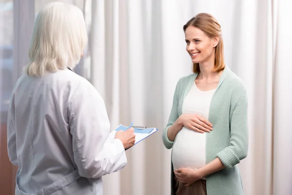 Médico con mujer embarazada durante la consulta - foto de stock