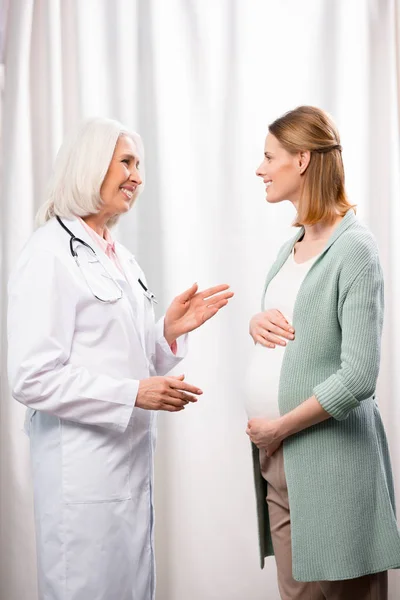 Mujer embarazada joven hablando con el médico - foto de stock