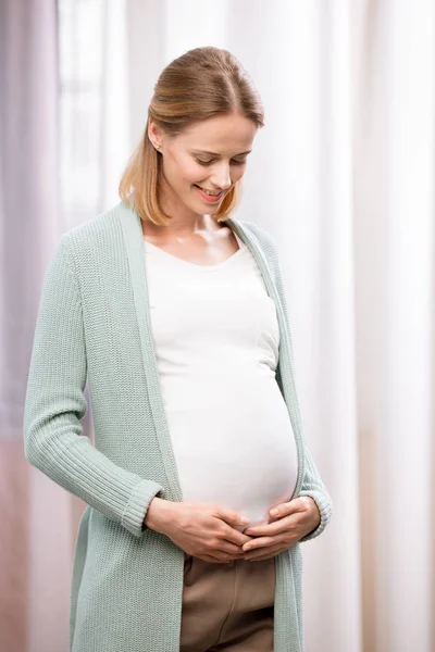 Mulher grávida feliz segurando estômago — Fotografia de Stock