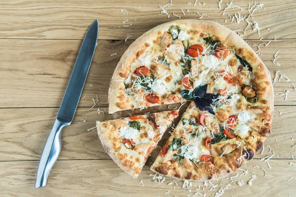 Pizza italienne avec couteau sur table en bois — Photo de stock