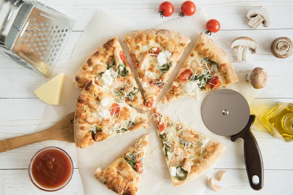 Pizza in Scheiben mit Käse und Küchenutensilien — Stockfoto