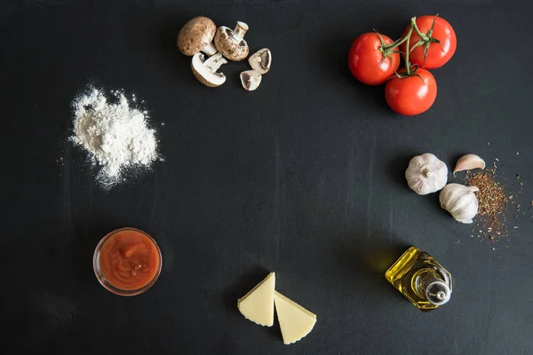 Ingredientes para preparar pizza en la superficie oscura - foto de stock